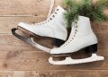 Vintage ice skates for figure skating with fir tree branch hanging on rustic background. Christmas decoration.